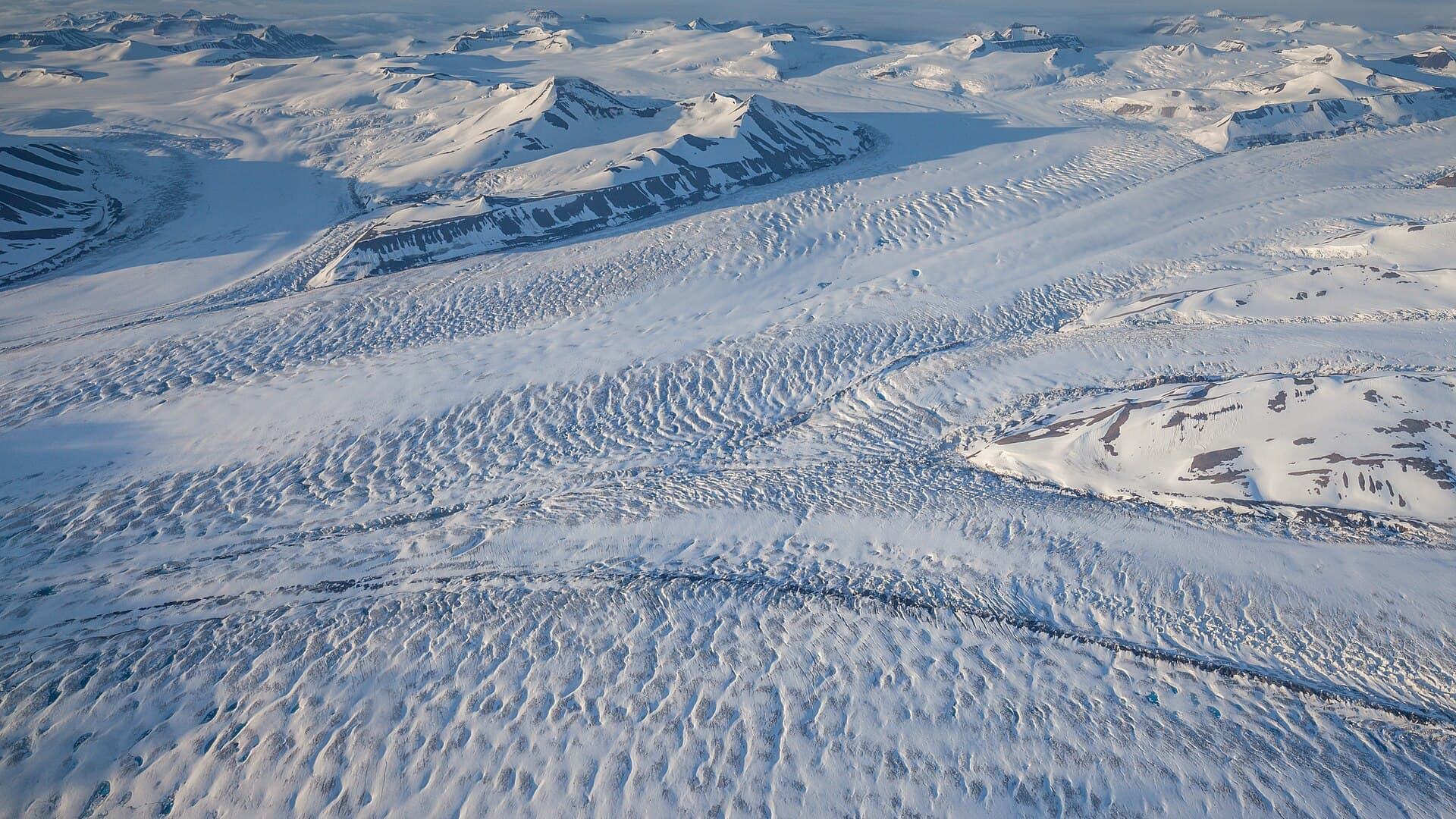 A glacier and pale sky under midnight sun, a reminder that latitude changes the light clock.