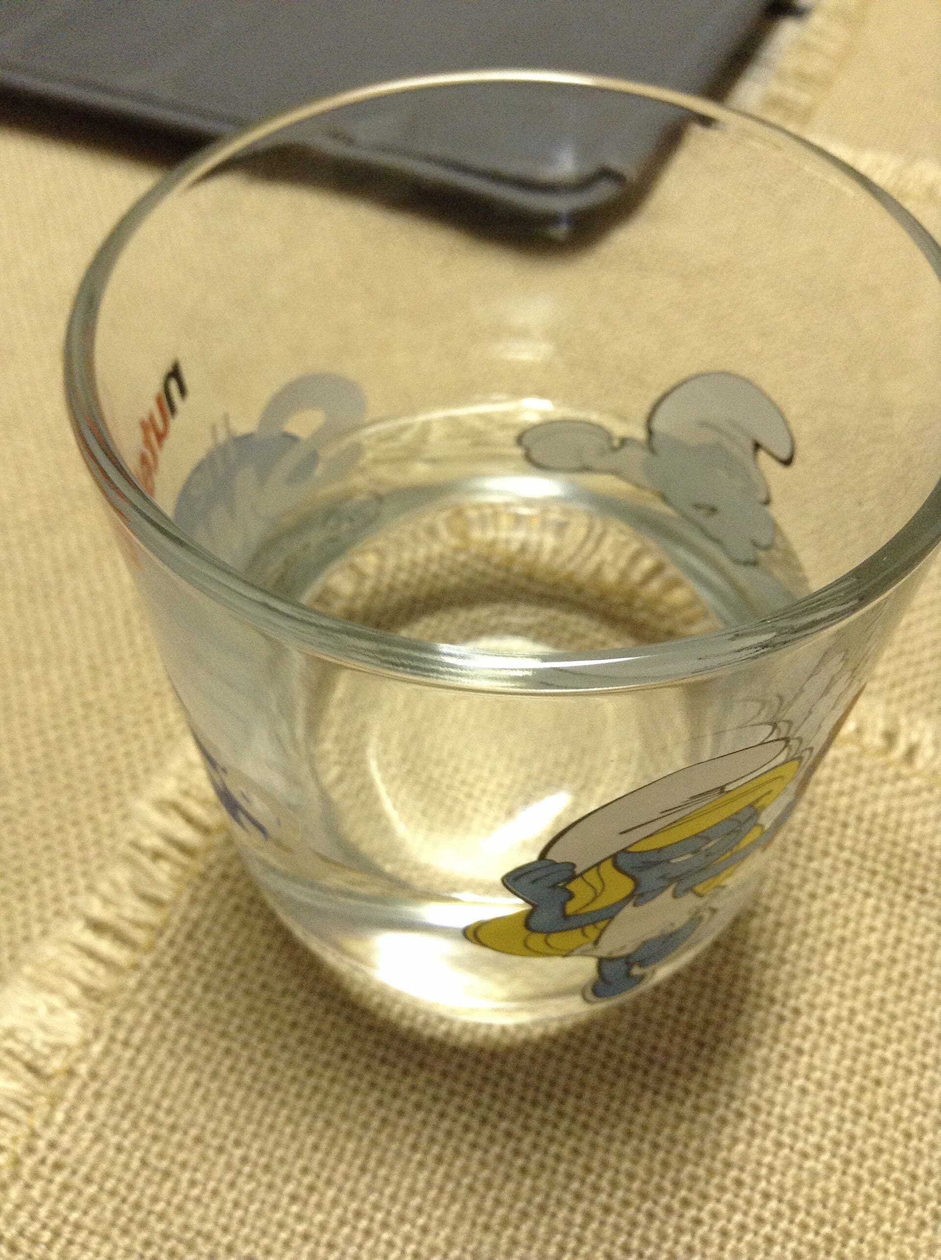 A clear glass of water on a plain surface.